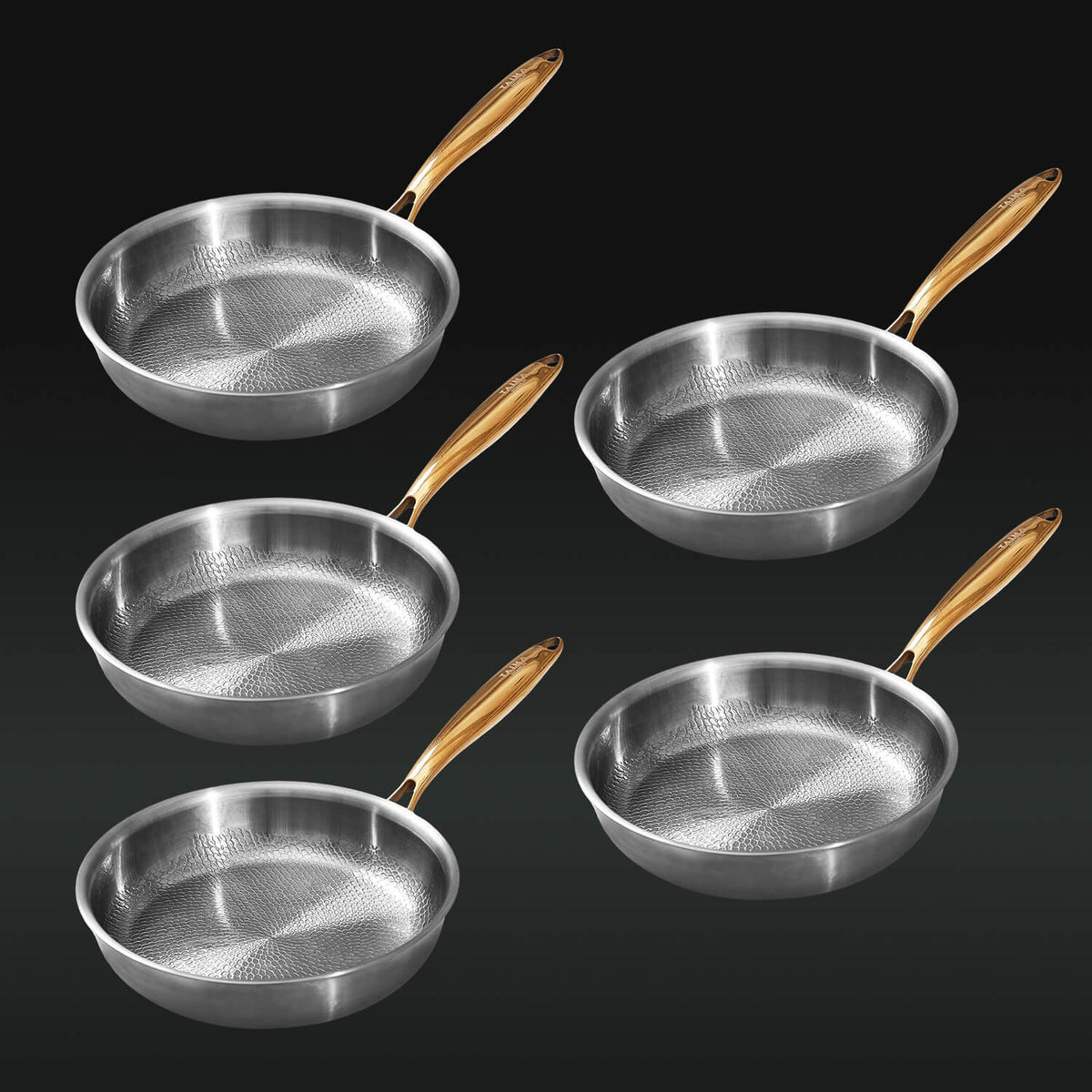 Set of five silver frying pans with gold handles on a black background