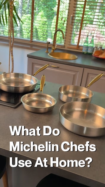 Three Titanium chef's pans with gold-toned handles arranged on a kitchen countertop in front of a sink and window. Large overlaid text reads, 'What Do Michelin Chefs Use At Home?'.